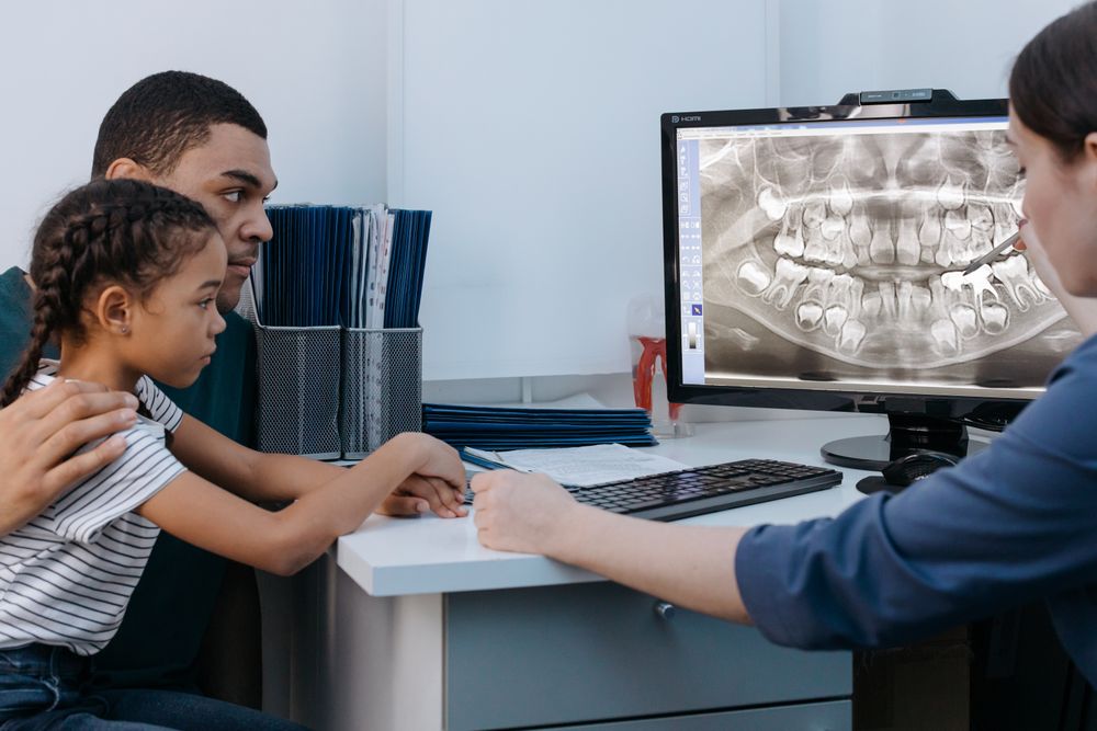 A parent and child reviewing a dental x-ray with the dentist